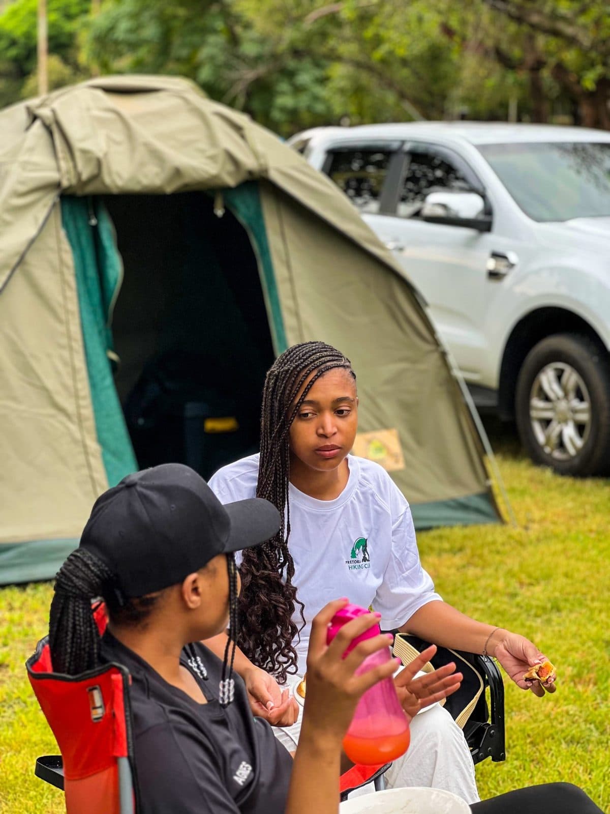 Two members sitting by a tent at a club camping weekend